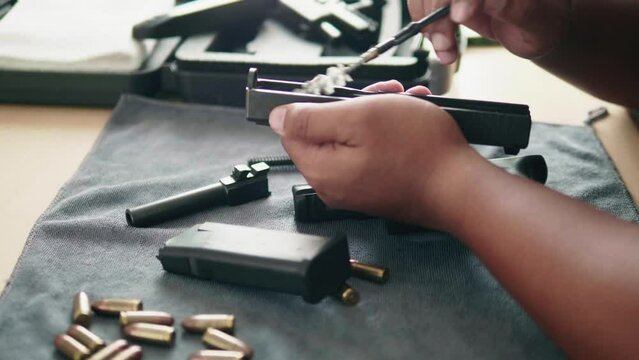 Care and maintenance.Black firearms were dismantled and cleaned by Asian men.Firearm dis-assembly for cleaning and safety check of handheld gun.Assembling the gun.Weapon care.High quality 4k footage