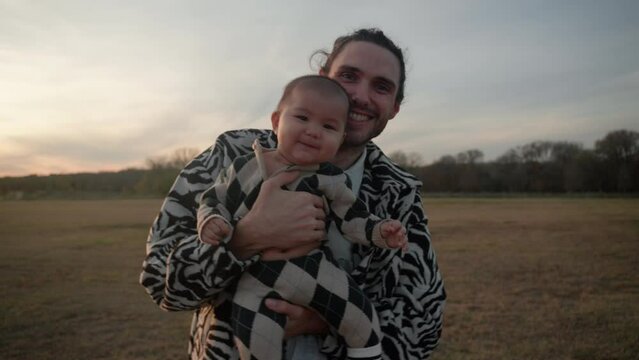 Portrait of white father bouncing his cute baby son outdoors to comfort him and make him happy. Slow motion