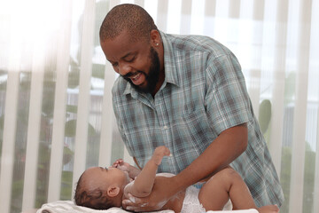 Happy African family, toddle baby infant lying on towel after taking a bath in bathroom, father...