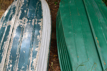 Two old green dinghy boats upturned against a bank