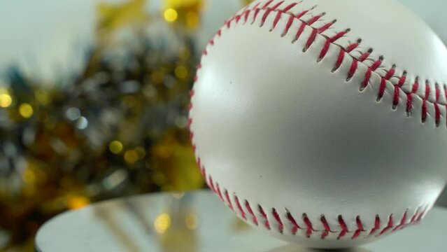 Cinematic slow close-up shot of a white base ball, red stitches  baseball on a shiny stand, Christmas blurry decorations in the background, professional studio lighting, 4K video pan right