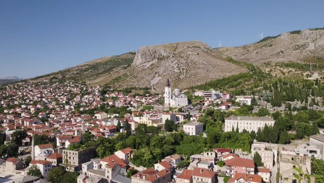 Aerial view of Mostar Cityscape with Cathedral of the Holy Trinity in distance, Orbiting Shot