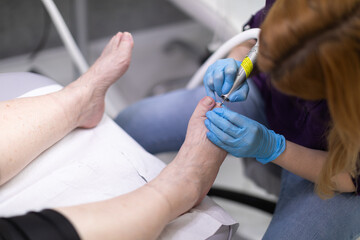 A beautician carefully performs a pedicure on a beauty salon client.