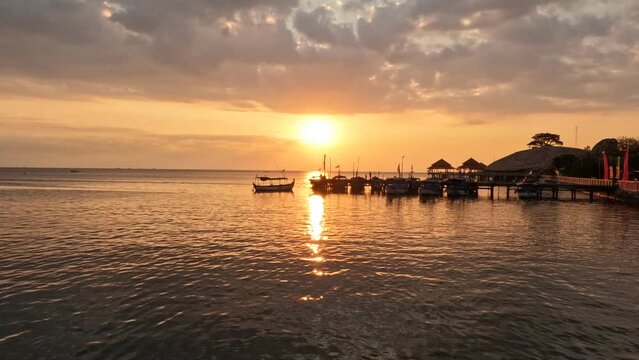 Beautiful timelapse of sunset view over sea surface beautiful wave. Amazing light sunset or sunrise sky over sea beach with fisherman's boat dock.