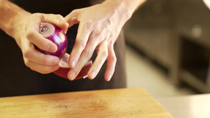 Chef carefully peels onion  using clean hands, demonstrating precision and hygiene