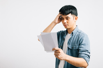 An Asian man, looking depressed and nervous, holds a document indicating financial accounts, clearly troubled and upset over bills. Studio shot on white. over bill