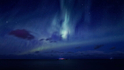 Lofoten winter landscape. A wide angle view of an islet in the sea under the northern lights in a...