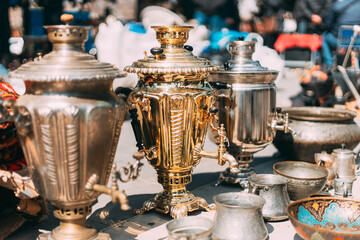 Shiny Bright Samovars Stand In A Row. Tea Party Concept And Hospitality. Traditional Russian Samovar At Flea Market. Vintage Copper Samovar. Since Ancient Times In Russia, All Guests Were Offered To - obrazy, fototapety, plakaty