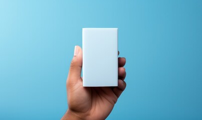 Hand holding small white rectangular box on blue background