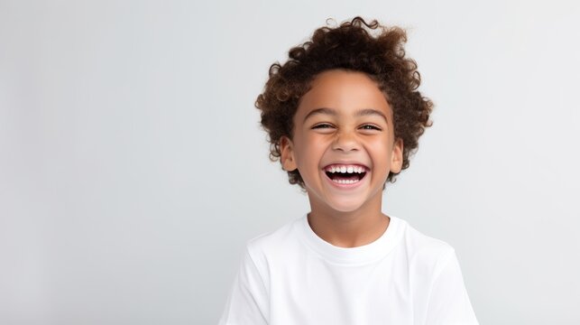 Fototapeta A professional portrait studio photo of a cute mixed race boy child model with perfect clean teeth laughing and smiling. isolated on white background