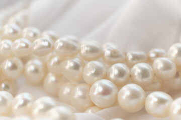 Pearls lay scattered on a white canvas, their natural glow a soft whisper of elegance. The image...