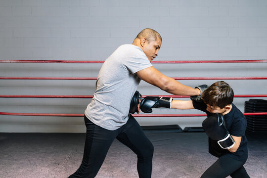 Horizontal photo elementary boy training in the ring with his boxing teacher. Sport concept.