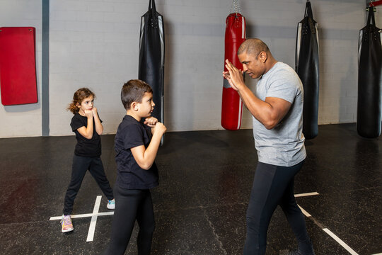 Horizontal photo elementary children with their teacher in a boxing school warming up. Sport concept