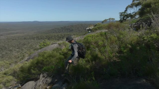 Man descending a high vantage point in the forest.