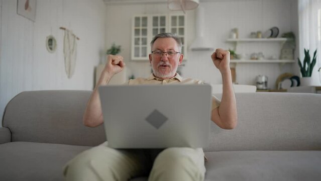 One man senior caucasian male with beard sit home in day with laptop computer making online purchase shopping buy stuff hold credit card pensioner enjoy his retirement. Older man with technology.