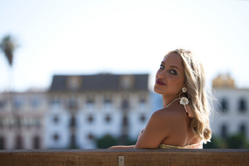 Young beautiful blonde woman sitting on a bench by the river bank in seville. The woman is relaxed...