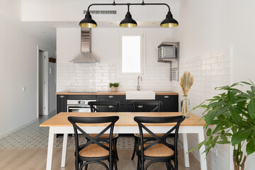 Horizontal shot of a black and white kitchen with a loft ceiling combined with a dining area overlooking the corridor. Concept of renovation in new building for a young couple