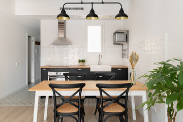 Horizontal shot of a black and white kitchen with a loft ceiling combined with a dining area...