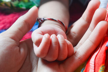 Close up of a newborn baby's hand being held by the mother as a sign of affection