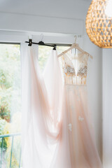 Detail of wedding dress hanging on a curtain by the window