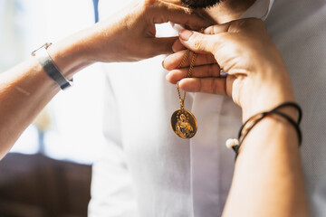 Detail of the groom's suit at the wedding, mother placing a religious brooch to give him luck at...