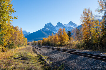 Railway scenery in fall season. The Three Sisters trio of peaks over the blue sky. Canmore,...