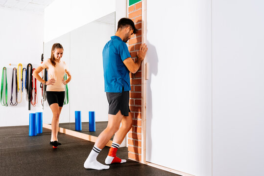 Young man with red sports protective floss band bandage on foot doing exercice at gym