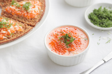 Appetizer with red caviar, sour cream, dill, onion and rye bread on the white table - the finnish recipe for a holiday food, flat lay in minimalistic style