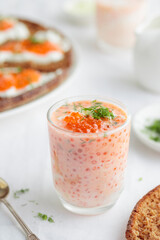 Appetizer with red caviar, sour cream, dill, onion and rye bread on the white table - the finnish recipe for a holiday food, close up in minimalistic style