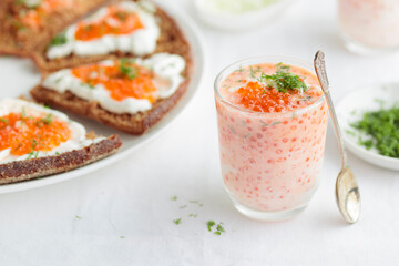 Appetizer with red caviar, sour cream, dill, onion and rye bread on the white table - the finnish recipe for a holiday food, close up in minimalistic style
