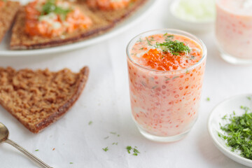 Appetizer with red caviar, sour cream, dill, onion and rye bread on the white table - the finnish recipe for a holiday food, close up in minimalistic style