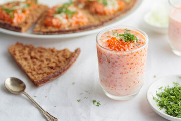 Appetizer with red caviar, sour cream, dill, onion and rye bread on the white table - the finnish recipe for a holiday food, close up in minimalistic style