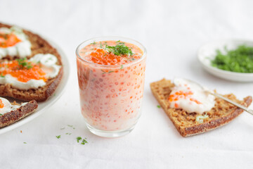 Appetizer with red caviar, sour cream, dill, onion and rye bread on the white table - the finnish recipe for a holiday food, close up in minimalistic style