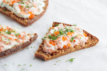 Appetizer with red caviar, sour cream, dill, onion and rye bread on the white table - the finnish recipe for a holiday food in minimalistic style