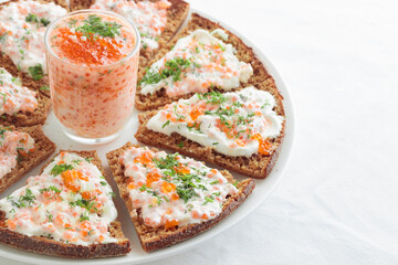 Appetizer with red caviar, sour cream, dill, onion and rye bread on the white table - the finnish recipe for a holiday food in minimalistic style
