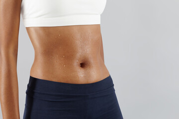 Fitness workout, woman sweaty abdomen, drops of sweat on skin belly Close up, African latin...