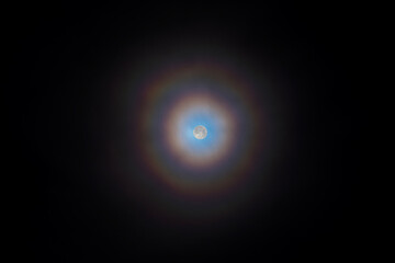 Glowing full moon at night with double rainbow halo, ring of light