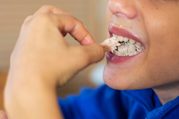 boy takes out stuck pieces of meat from his teeth with his hands