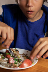 boy eats buckwheat porridge with vegetable salad and meat with a fork