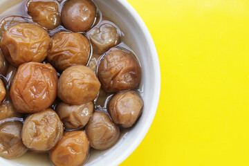 Pickled plums on yellow background.