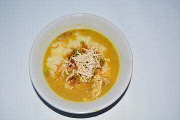 Close up of chicken porridge topped with crackers, nuts and fried foods