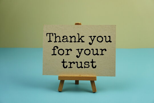 Thank you for your trust text message written on paper card with alarm clock on blue and yellow background
