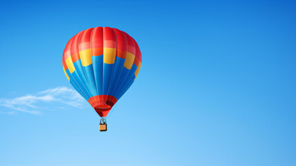 Fototapeta na wymiar Colored hot air balloon on a clear blue sky with few clouds 