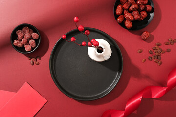 On a red backdrop, salted dried fruit, jujubes, an empty dish, ribbons, red envelopes, and a flower...