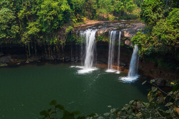 Obraz premium Three waterfalls flowing from the rocks among the trees in the forest. Bolaven Plateau, Laos