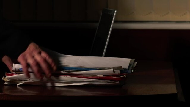 Looking at pile of paper files on desk in dark room 