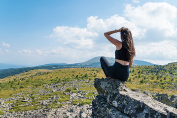 Naklejka na ściany i meble Woman sitting on a rocks in the summer mountain