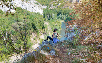Naklejka na ściany i meble Woman sitting above river in the summer mountain 