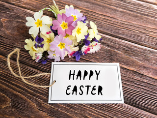 Happy Easter card with spring primroses on wooden background  