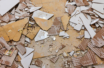 Top view of the floor of a house under demolition with pieces of broken ceramic bricks in shades of...